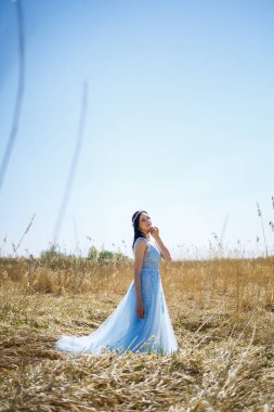 Sıcak bir yaz gününde yüzünde bir gülümsemeyle, kuru bezelyelerle mavi uzun bir elbise içindeki hassas bir kızın portresi.