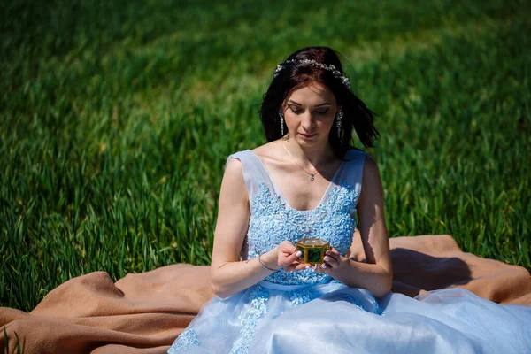 Young Woman Blue Long Dress Sits Green Field Casket Her — Stock Photo, Image