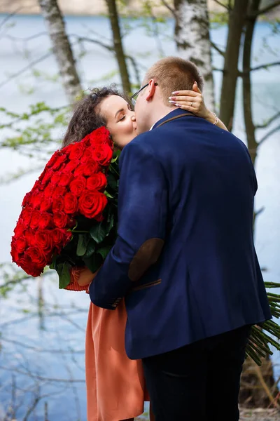 젊은이들의 낭만적 꽃다발이 정장을 남자가 여자에게 꽃다발을 숲에서 키스를 — 스톡 사진