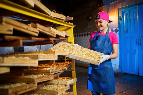 Make the noodles. Pasta factory. Spaghetti production. Raw pasta. Worker with a box of pasta. Girl works in the production of pasta