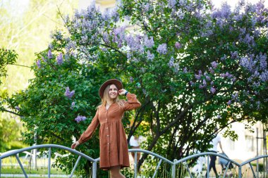 Güzel, uzun saçlı, şapkalı, leylak çiçekli bir kız.