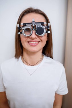 Göz doktorunun randevusundaki genç ve güzel kadın gözlerini kontrol ediyor. Doktor göz doktoru hastayı muayene ediyor.