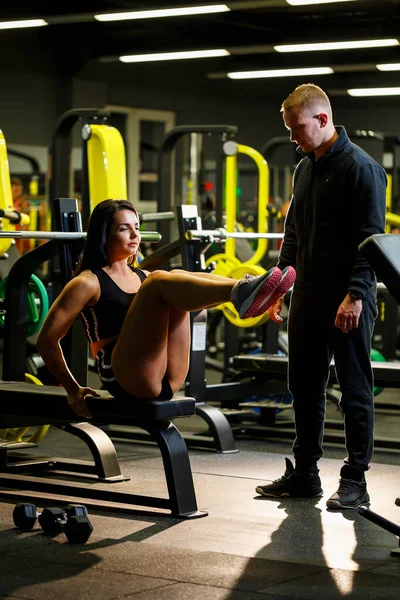 Girl doing exercises in the gym with a trainer