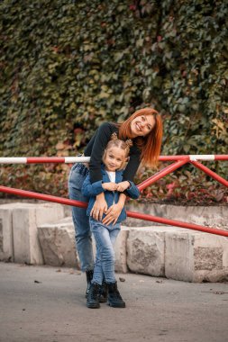 Şık kızıl saçlı anne ve kızı samimi bir şekilde konuşuyorlar. Mutlu çocuk ve annesi sokakta. Kızıyla yürüyüşe çıkan başarılı bekar anne. Sıcak aile ilişkisi