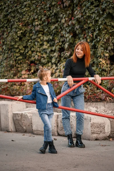 スタイリッシュな赤い髪の母親と彼女の娘は暖かく話しています 路上で幸せな子供と彼女の母親 散歩のための彼女の娘との成功したシングルマザー 暖かい家族関係 — ストック写真