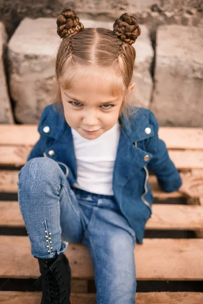 Uma Linda Menina Está Sentada Roupas Elegantes Paletes Madeira Criança — Fotografia de Stock