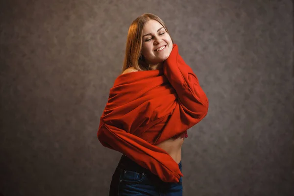 女の子試行上の赤いセーター上の灰色の背景 — ストック写真
