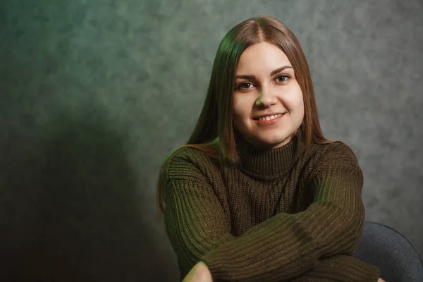 Chica Suéter Verde Jeans Una Silla Gris Sonriendo —  Fotos de Stock