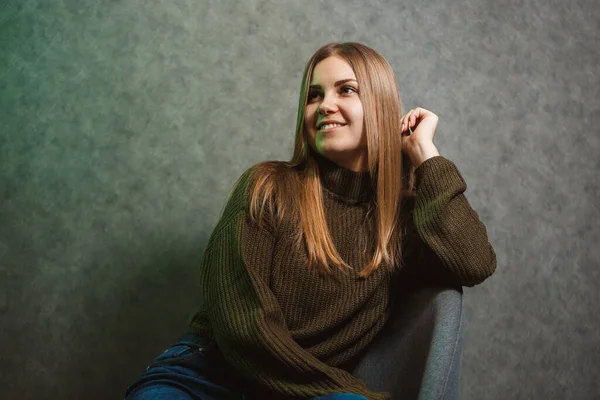 Chica Suéter Verde Jeans Una Silla Gris Sonriendo — Foto de Stock