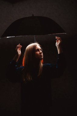 Karanlık ışıkta şemsiye altındaki siluet kız.