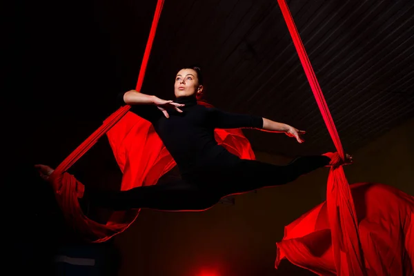 Girl aerialist doing twine on aerial canvases. Acrobatics in the air