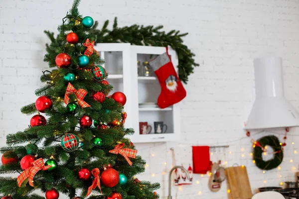 New Year decorations in the kitchen: a green tree decorated with red and green balls, New Year decorations, yellow garlands. New Year. Decorating the house for Christmas