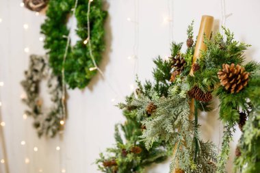 Duvarda bir Noel ağacının dallarından yeni yıl çelengi asılı. Yeni yıl için ev dekorasyonları. Yılbaşı tatili için odayı dekore ediyorum.