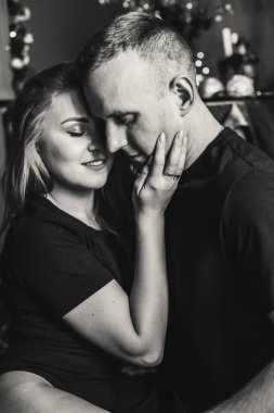 Yeni yıldan önce evde çelenklerle vakit geçiren tutkulu romantik bir çiftin görüntüsü. Genç kadın ve yakışıklı erkek sarılır, öpüşür. Noel zamanı.