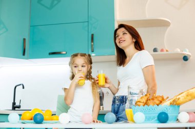 Genç, güzel anne ve küçük kızı evde kahvaltıda mutfakta oynuyorlar..