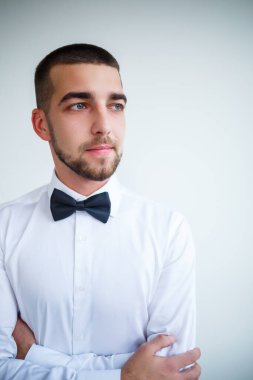 Kısa sakallı beyaz gömlekli genç erkek işadamı siyah papyon takıyor.