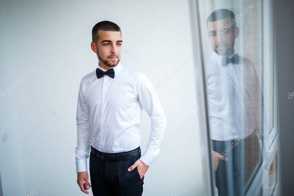 Young male businessman dressed in a white shirt with a short beard wears a black bow tie