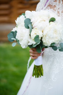 Güzel gelin, düğün günü elinde bir buket çiçek tutuyor.