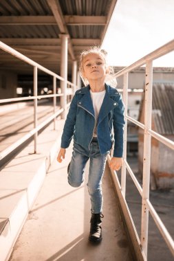 Kot elbiseli kız otoparkta hip-hop dansı yapıyor.