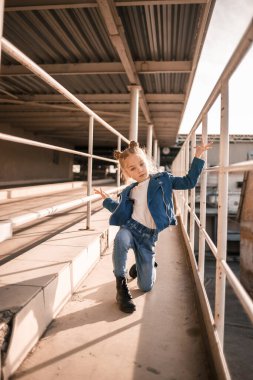 Kot elbiseli kız otoparkta hip-hop dansı yapıyor.