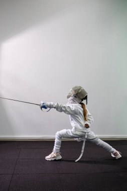 Çocuklar kılıçlarla saldırır. Eskrim okulunda bir çocuk.