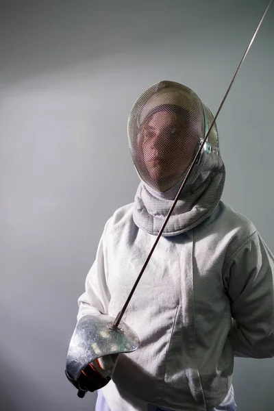 Fille dans un costume d'escrime avec une épée à la main isolé sur fond de studio blanc. Les jeunes filles pratiquent et font de l'exercice. Sport, mode de vie sain. — Photo