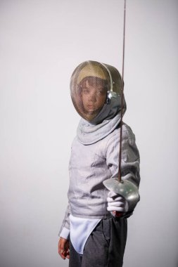 Elinde kılıçla eskrim kıyafeti giymiş bir kız. Genç bayan model pratik ve egzersiz yapıyor. Spor, sağlıklı yaşam tarzı..