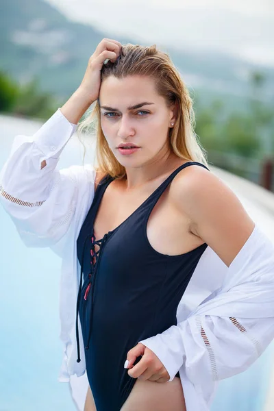 Retrato de una joven atractiva con el pelo rubio en un traje de baño negro y camisa blanca —  Fotos de Stock