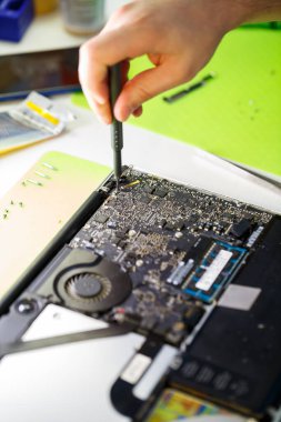 Adam dizüstü bilgisayarı tozdan özel bir aletle temizliyor. Elektronik ve aygıtların onarımı için dizüstü bilgisayarların ve bilgisayar reklamlarının onarımı ve bakımı.