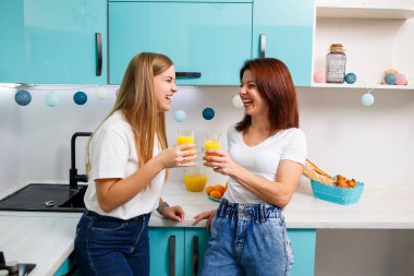Mutfakta dikilip portakal suyu içen iki kadın arkadaş. Kız arkadaşlar sohbet eder, mutfakta sırlarını paylaşırlar, kahvaltı yaparlar.