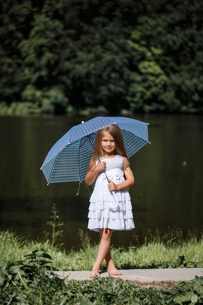 白いドレスを着た長髪の少女が川のほとりに立っている 夏の晴れた日に湖を歩く — ストック写真