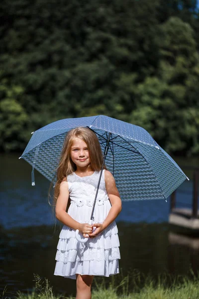 白いドレスを着た長髪の少女が川のほとりに立っている 夏の晴れた日に湖を歩く — ストック写真