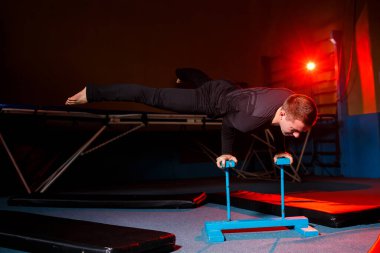 Spor giyimli bir jimnastikçinin portresi, spor salonunda at üstünde egzersiz yapan bir adam.