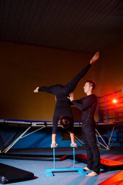Genç kadın ve erkek jimnastikçiler spor salonunda akrobatik egzersizler yaparlar. Spor aktiviteleri, sağlıklı yaşam tarzı.