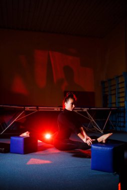 Genç bir kadın sicim oturma alıştırması yapıyor. Spor salonunda jimnastik yapan atletik kız. Etkin yaşam biçimi