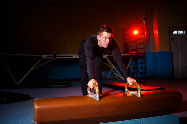 Young strong man doing handstand exercises. Male gymnast doing sports in the gym