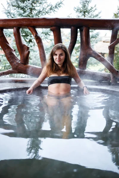 屋外ジャグジー 女の子とジャグジー 水着姿の美しい女性 テラスでお湯でプールの女の子 スパボディトリートメント 開放的な空気の中でリラックスしてください 温泉付きコテージ — ストック写真