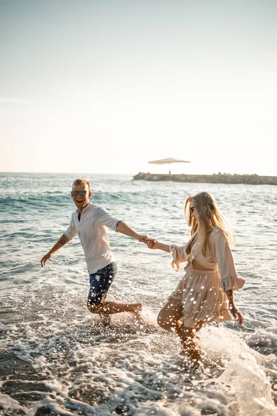 夏休みと旅行 日没時に海の水の中でセクシーな女性と男 恋人同士で日の出のビーチでリラックス 夏の日を一緒に楽しむカップルの愛の関係 — ストック写真