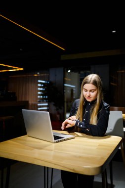 Modern kadın işadamının normal çalışma günü. Güzel genç bir kadın iş yerinde otururken elinde bir fincan kahve tutuyor.