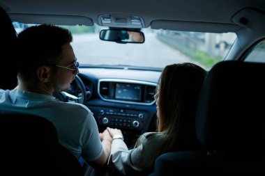 Sevgi dolu bir çift arabada el ele tutuşuyor. Avrupa görünümlü sarı saçlı şık bir genç kız ve beyaz polo giyen bir adam. Mutlu İlişkiler