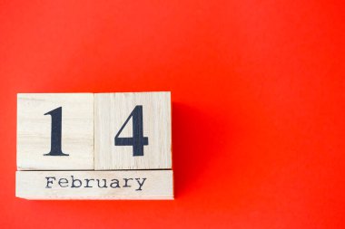 Parlak kırmızı zemin üzerinde 14 Şubat tarihli ahşap takvim. Romantik bir randevu. Sevgililer Günü konsepti. Üst görünüm, alanı kopyala.