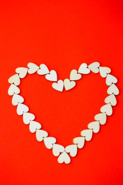 Parlak kırmızı arka planda tahta kalplerle dolu bir kalp. Sevgililer Günü için bir yazı, romantik bir resim.