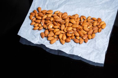 Lezzetli kavrulmuş tatlı bademler büyük bir yığın içinde, fındıklar yakın planda yatıyor..