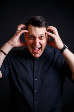 Tıbbi giysiler içindeki genç bir erkek doktorun duygusal yakın plan portresi. Siyah arkaplanda izole