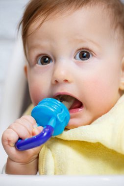 Küçük bir çocuk yüksek bir sandalyeye oturur ve ağdan meyve yer. Bebekleri beslemek için Nibbler