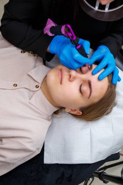 Güzellik salonunda gür kaşları olan güzel bir kadının yüzü. Kaşlar için kalıcı makyaj. Güzellik uzmanı kadınlar için kaş dövmesi yapar. Güzellik prosedürü.