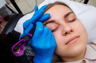 Güzellik salonunda gür kaşları olan güzel bir kadının yüzü. Kaşlar için kalıcı makyaj. Güzellik uzmanı kadınlar için kaş dövmesi yapar. Güzellik prosedürü.