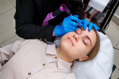 Güzellik salonunda gür kaşları olan güzel bir kadının yüzü. Kaşlar için kalıcı makyaj. Güzellik uzmanı kadınlar için kaş dövmesi yapar. Güzellik prosedürü.