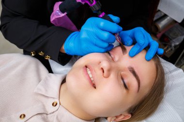 Güzellik salonunda gür kaşları olan güzel bir kadının yüzü. Kaşlar için kalıcı makyaj. Güzellik uzmanı kadınlar için kaş dövmesi yapar. Güzellik prosedürü.