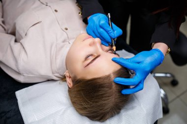 Makyaj sanatçısı, kaş kalemi olan genç bir kızın kaşlarına bir çizim uygular. Profesyonel makyaj ve estetik cilt bakımı.